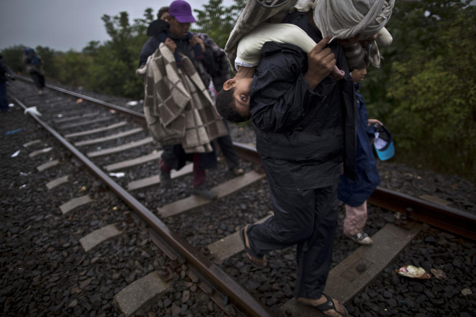 <p>Bara’ah Alhammadi, 10, a Syrian migrant, is carried on the back of her father as they make their way along a railway track after crossing the Serbian-Hungarian border near Roszke, southern Hungary, Sept. 11, 2015. (Photo: Muhammed Muheisen/AP) </p>