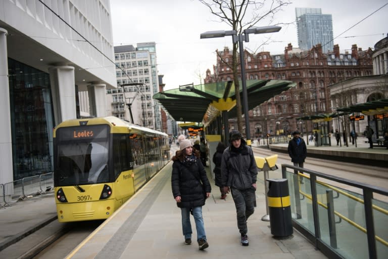 People disembark from a tram in St Peter's Square in the city centre of Manchester, northwest England