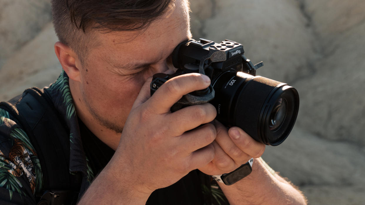  Panasonic Lumix S 100mm f2.8 Macro lens  attached to a Panasonic camera held in a person's hands. 