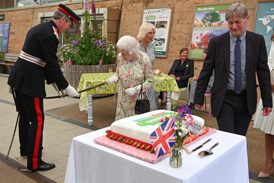 ST AUSTELL, ENGLAND - JUNE 11: Queen Elizabeth II (C) takes a sword from The Lord-Lieutenant of Cornwall, Edward Bolitho (L) in order to cut a cake to celebrate of The Big Lunch initiative at The Eden Project during the G7 Summit on June 11, 2021 in St Austell, Cornwall, England. UK Prime Minister, Boris Johnson, hosts leaders from the USA, Japan, Germany, France, Italy and Canada at the G7 Summit. This year the UK has invited India, South Africa, and South Korea to attend the Leaders' Summit as guest countries as well as the EU. (Photo by Oli Scarff - WPA Pool / Getty Images)