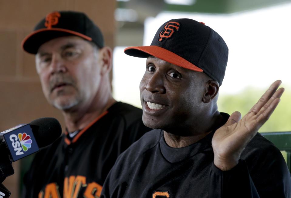 San Francisco Giants manager Bruce Bochy, left, listens as former player Barry Bonds speaks at a news conference before a spring training baseball game in Scottsdale, Ariz., Monday, March 10, 2014. Bonds starts a seven day coaching stint today. (AP Photo/Chris Carlson)