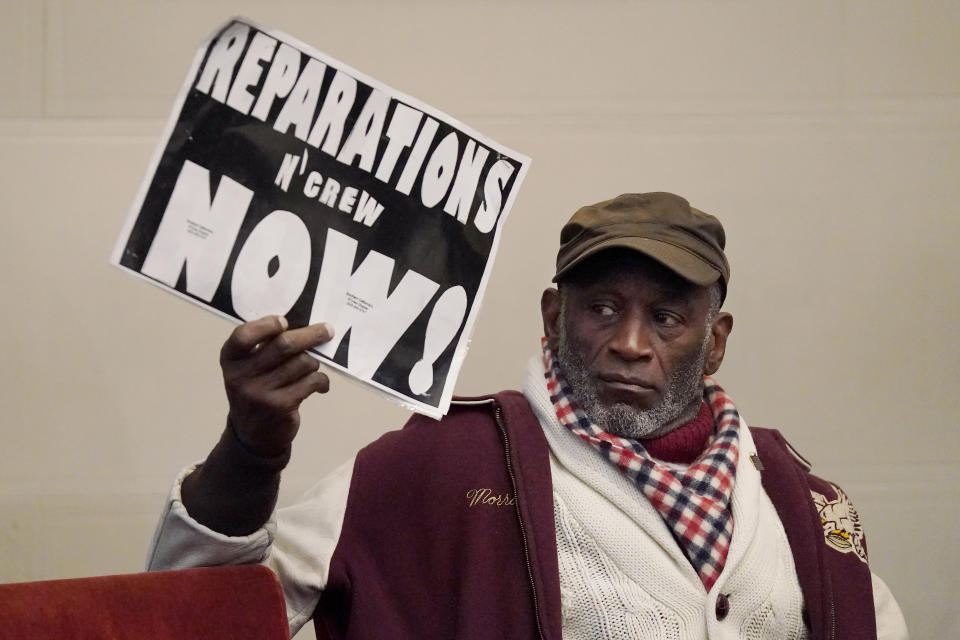 Morris Griffin holds up a sign during a meeting by the Task Force to Study and Develop Reparation Proposals for African Americans in Oakland, Calif., Wednesday, Dec. 14, 2022. (AP Photo/Jeff Chiu)