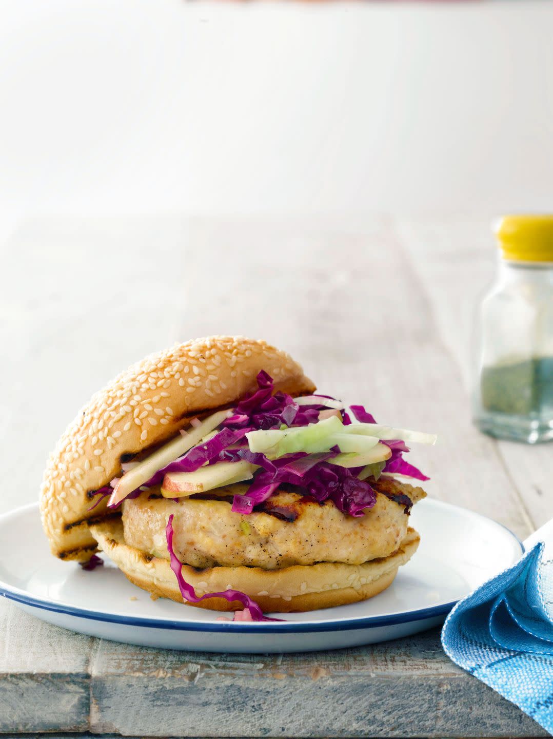 miso glazed chicken burgers with cabbage apple slaw on a white plate with navy trim