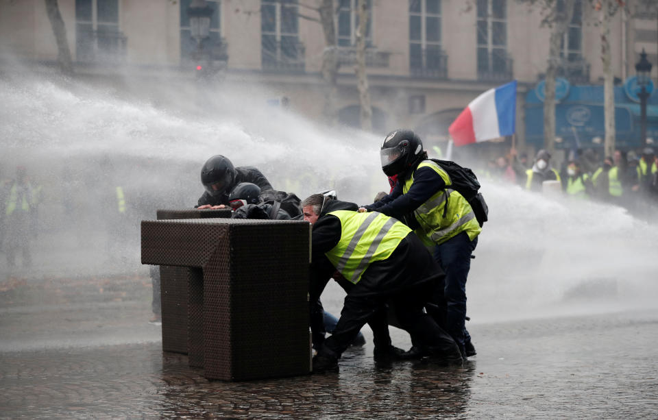 Protesters stand up in front of a police water canon during clashes. Source: Benoit Tessier/Reuters