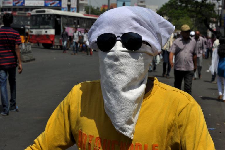 An Indian man shields his face from the heat as drives his scooter in Hyderabad on May 26, 2015