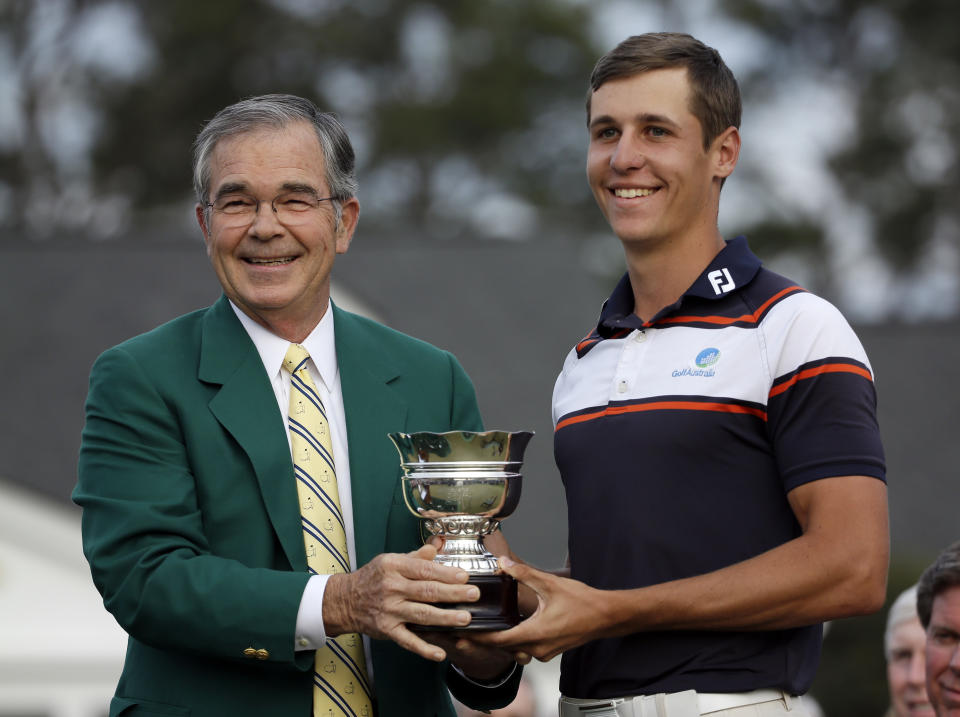 Amateur Oliver Goss, of Australia, is given his trophy by Billy Payne, Chairman of the Augusta National Golf Course, following the Masters golf tournament Sunday, April 13, 2014, in Augusta, Ga. (AP Photo/David J. Phillip)