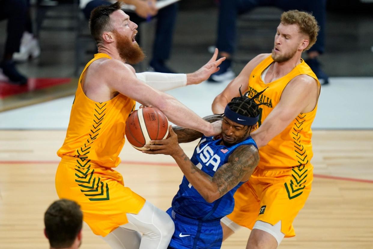 United States’ Bradley Beal drives into Australia’s Aron Baynes, left, and Jock Landale, right, during an exhibition basketball game Monday, July 12, 2021, in Las Vegas. (AP Photo/John Locher).