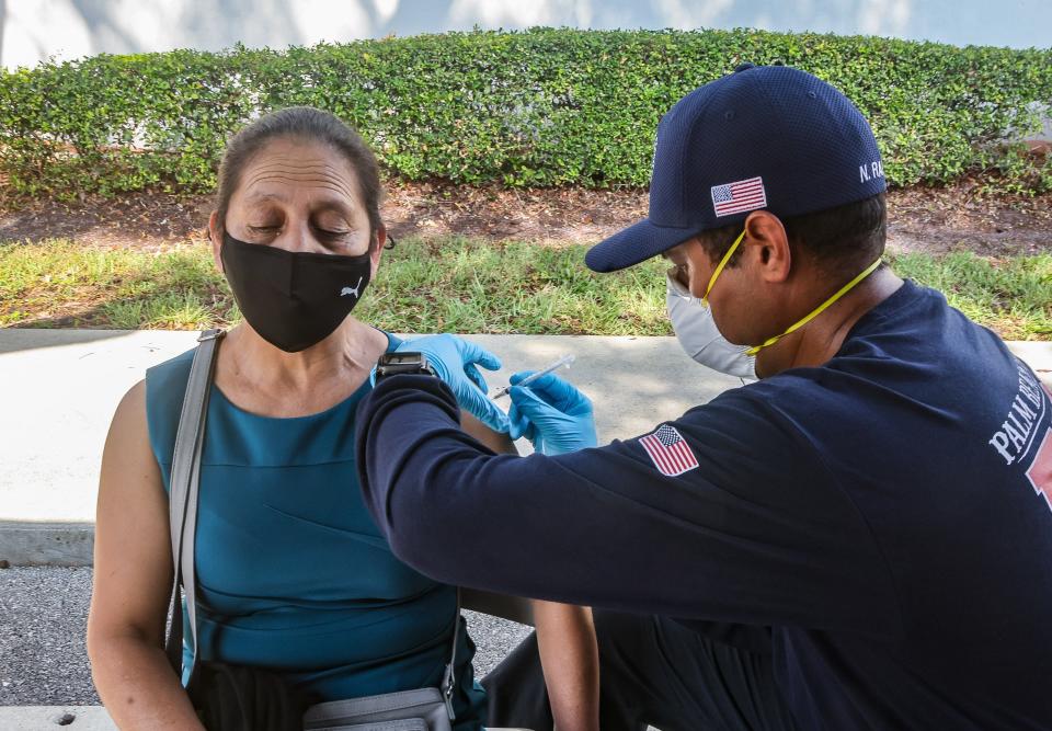 Spanish speaker Rosita Zapeta, 55, receives a Covid-19 vaccination from Palm Beach County firefighter Nelson Ramirez outside the Palm Beach County Public Health Department in Lantana, FL, July 28, 2021. The vaccinations were being organized by the Health Care District of Palm Beach County.