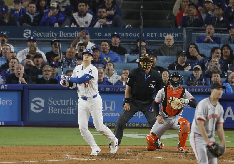 Shohei Ohtani watches his first home run as a Dodger flies well over the fence.