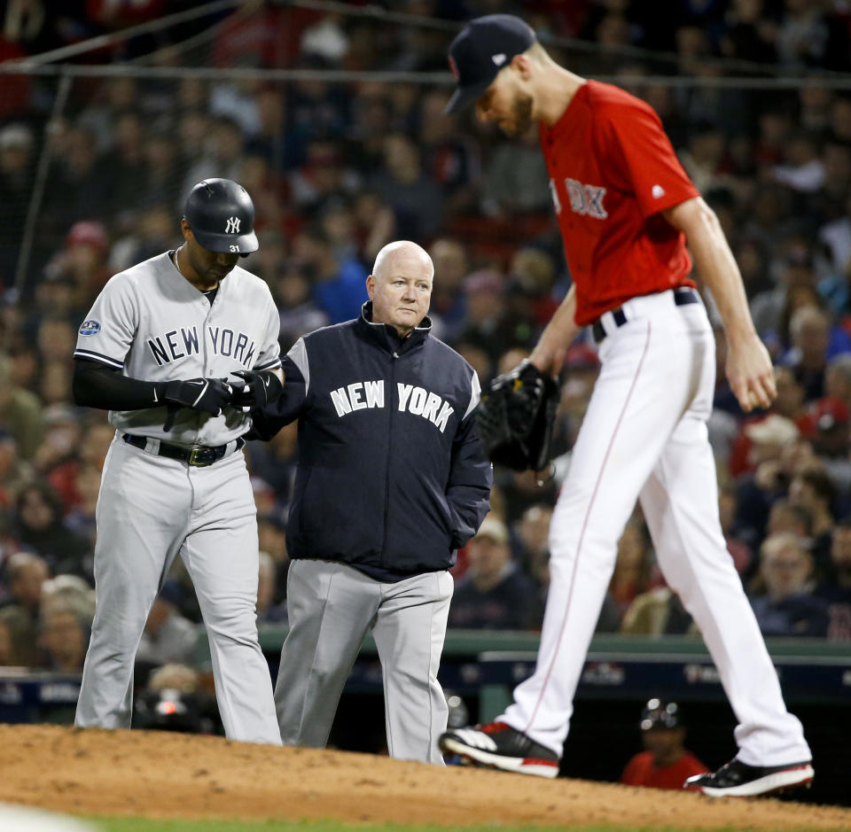 New York Yankees' Aaron Hicks, left, is helped off he field after getting hurt during the fourth inning of Game 1 of the baseball team's American League Division Series against the Boston Red Sox on Friday, Oct. 5, 2018, in Boston. (AP Photo/Elise Amendola)