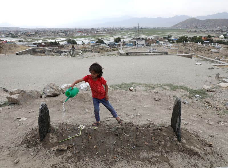 A girl spills water over the grave of twenty-four-year old Fatima Khalil, known as 'Natasha', who was killed in a bomb blast on Saturday, in Kabul