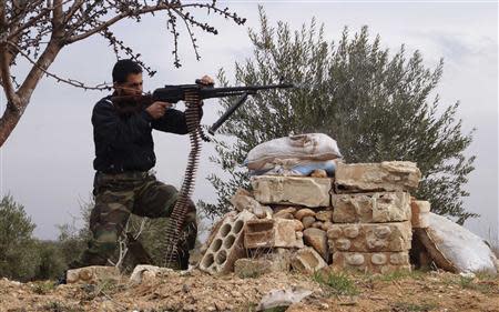 A Free Syrian Army fighter takes a position as he fires his weapon during clashes with forces loyal to Syria's President Bashar al-Assad in the town of Souran in the north Hama countryside February 15, 2014. REUTERS/Stringer