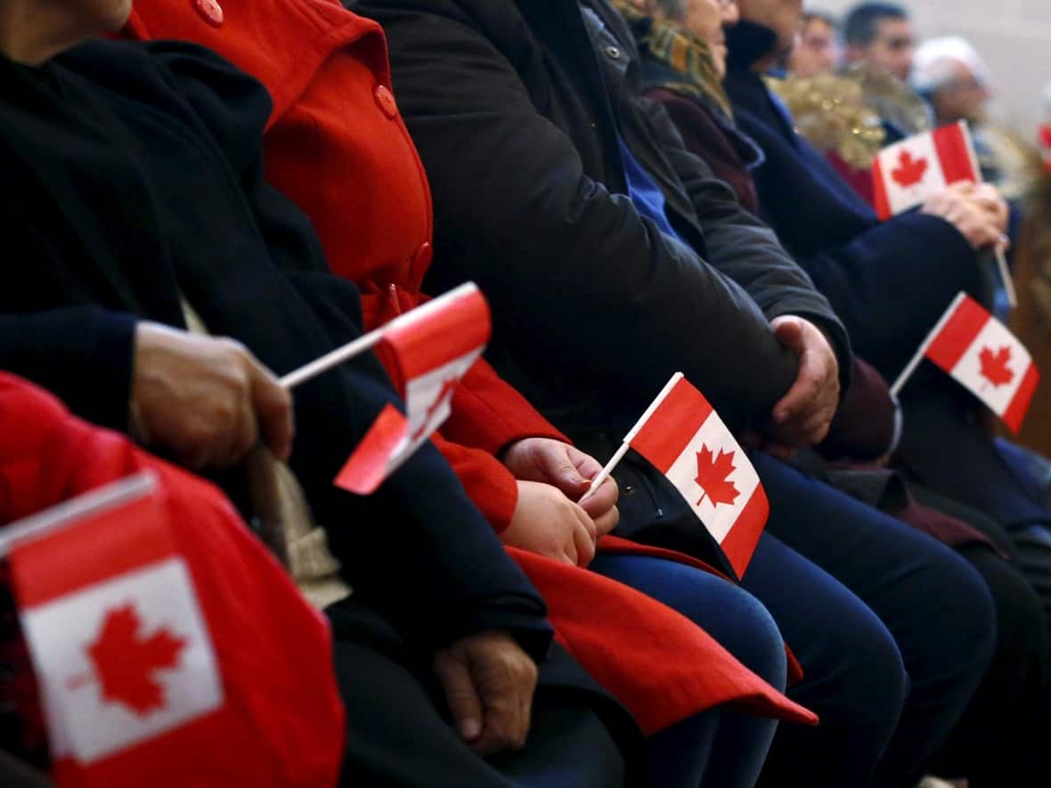 Syrian refugees hold Canadian flags as they take part in a welcome service in Toronto, on Dec. 11, 2015. Ottawa is developing a program that would provide a path to permanent residency for up to 500,000 immigrants, including those whose refugee applications may have been denied. (Mark Blinch/Reuters - image credit)