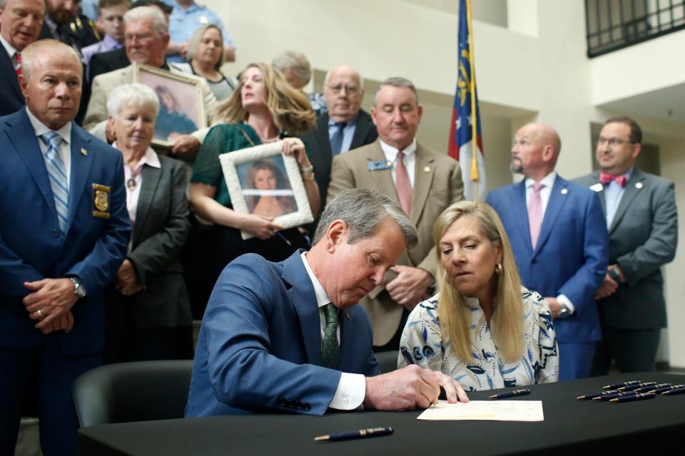 Gov. Brian Kemp signs HB 88, the Coleman-Baker Act, at the Athens-Clarke county court house in downtown Athens on Friday. The bill allows families of homicide victims to request law enforcement agencies to review cold cases.