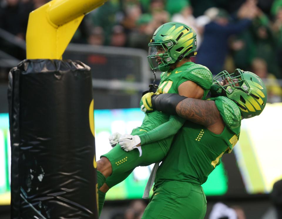 Oregon's Kris Hutson, left, is lifted into the air by offensive lineman George Moore after scoring against Oregon State in the fourth quarter.