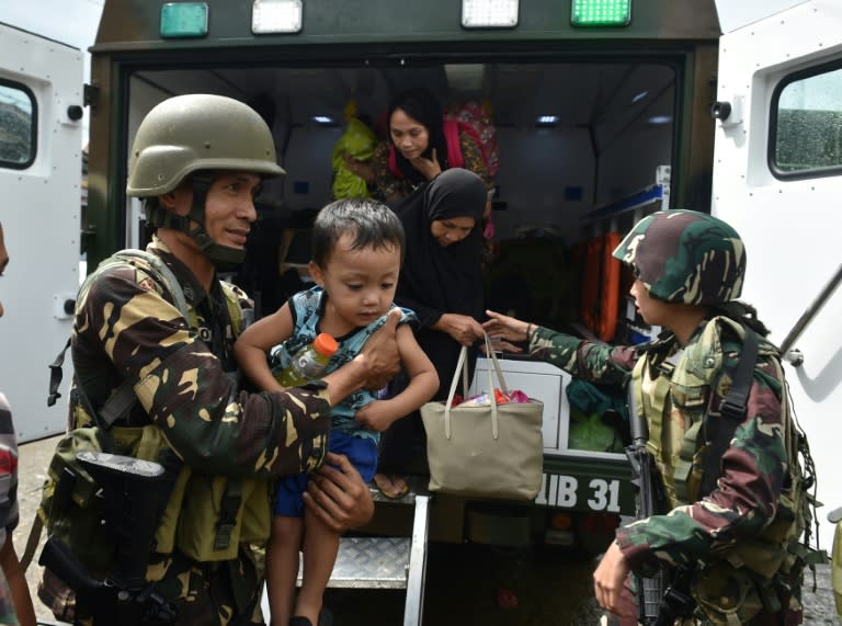 Evacuated residents are helped by military troopers disembark from a military vehicle shortly after arriving at a processing center near a hospital in Marawi, on southern Philippine island of Mindanao, on June 21, 2017