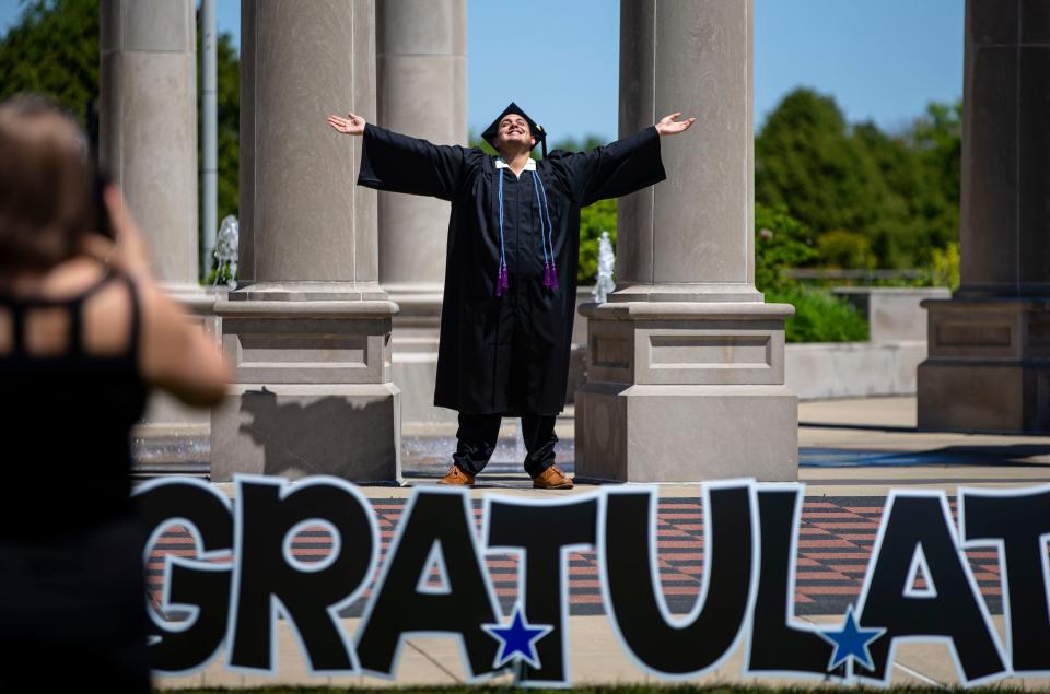 Oscar Mercado, of Palatine, Ill., celebrates his graduation next the Colonnade at the University of Illinois Springfield.