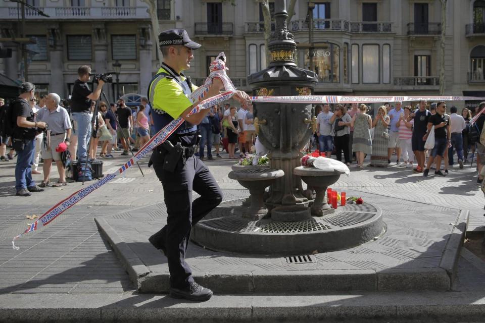 A police officer removes tape from Las Ramblas, next to the Canaletas fountain (AP)