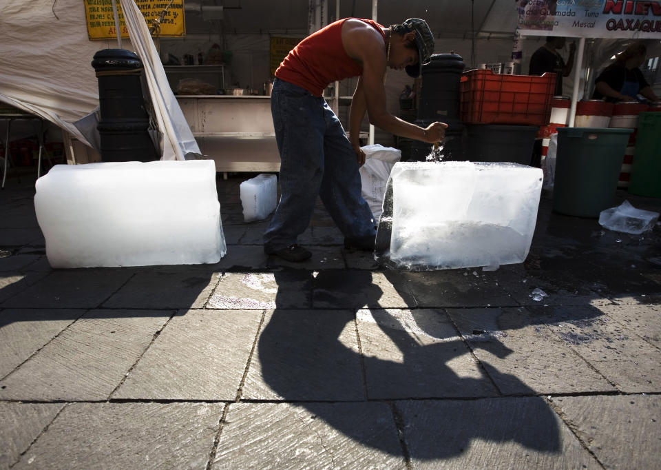 FILE - A street vendor breaks blocks of ice to be used to cool beverages for sale in downtown Mexico City, Wednesday, April 8, 2008, as the country experiences unusually hot weather for this time of the year, with highs of 81 degrees Fahrenheit. (AP Photo/Alexandre Meneghini, File)