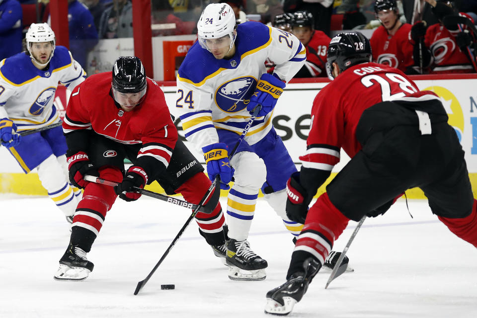 Buffalo Sabres' Dylan Cozens (24) maintains control of the puck between Carolina Hurricanes' Brendan Smith (7) and Ian Cole (28) during the first period of an NHL hockey game in Raleigh, N.C., Thursday, April 7, 2022. (AP Photo/Karl B DeBlaker)