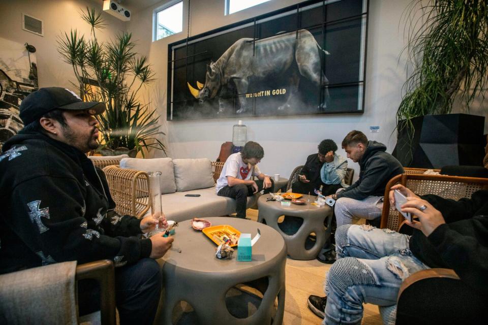 Five people in a living room setting smoking and vaping cannabis.