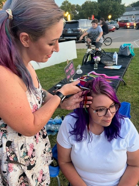 Sara Sosnowski puts a colorful extension in the hair of Lauren Holland at 2023 Bartlesville Pride.