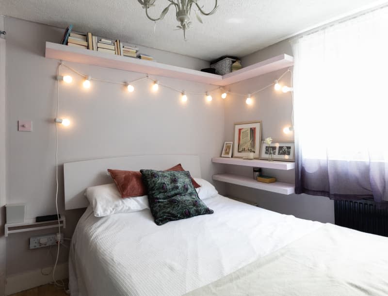 String lights hung above a bed in a simple white room