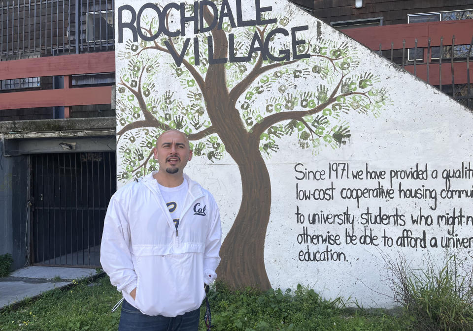 Jonathan Dena, 29, transfer student and senior at University of California, Berkeley poses outside the Rochdale Village Apartments where lives on March 17, 2022. Dena pays under $1,300 a month for a studio and parking at the apartments, but the bare bones and heavily subsidized units near campus operated by the Berkeley Student Cooperative are scheduled for seismic upgrades, which means Dena will need to move. He is on scholarship, and can't find anything for the $1,600 monthly rent allotted by his aid. (AP Photo/Janie Har)