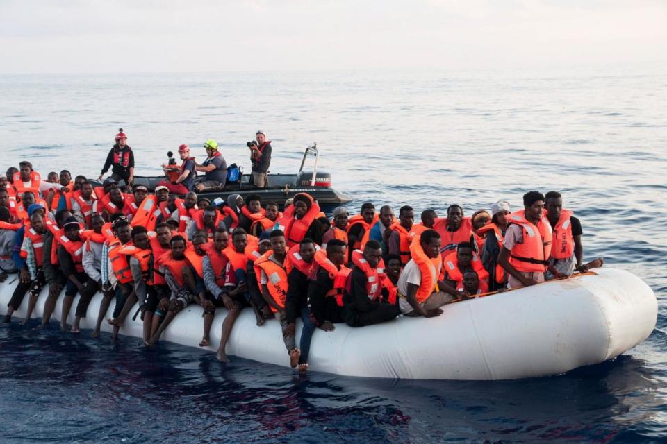 Lifeline: migrants on a rubber boat are rescued by the ship in the Mediterranean Sea in front of the Libyan coast (AP)