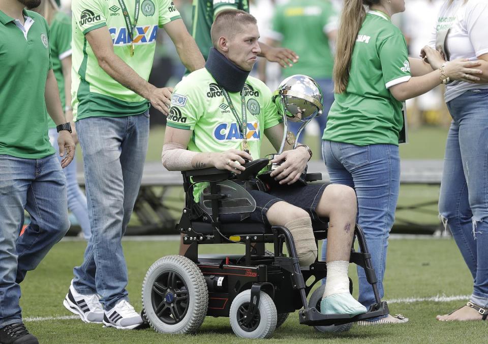 Chapecoense goalkeeper Follmann, one of the three players that survived the air crash almost two months ago, is wheeled on the pitch as he carries the Sudamericana trophy, during the Sudamericana trophy award ceremony prior to a match against Palmeiras, in Chapeco, Brazil, Saturday, Jan. 21, 2017. Almost two months after the air tragedy that killed 71 people, including 19 team players, Chapecoense plays at its Arena Conda stadium against the 2016 Brazilian champion Palmeiras. (AP Photo/Andre Penner)