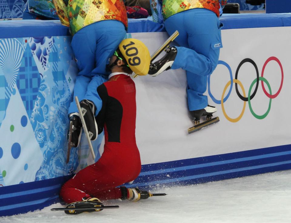 RNPS YEAR END 2014 - BEST OF SPORT ODDLY Olympic officials who maintain the ice jump out of the way as China's Kexin Fan crashes out into the barrier in the women's 500 metres short track speed skating semifinal event at the Iceberg Skating Palace during the 2014 Sochi Winter Olympics in this February 13, 2014 file photo. REUTERS/David Gray/Files (RUSSIA - Tags: SPORT OLYMPICS SPEED SKATING TPX IMAGES OF THE DAY)