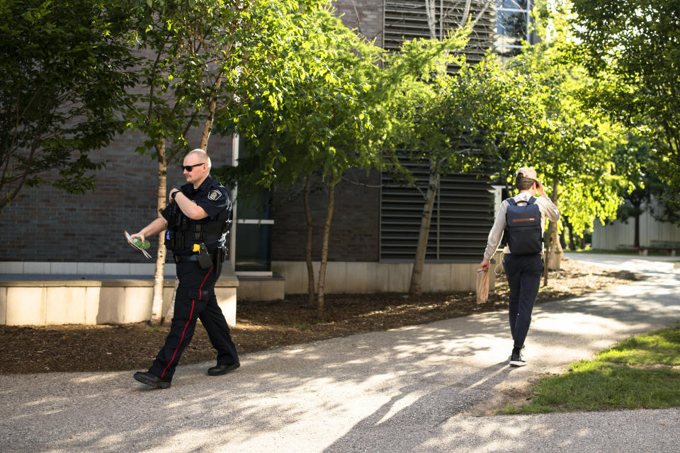 A member of the Waterloo Regional Police walks on campus following a stabbing at the University of Waterloo, in Waterloo, Ontario, Wednesday, June 28, 2023. Police said three victims were stabbed inside the university's Hagey Hall, and a person was taken into custody. (Nick Iwanyshyn/The Canadian Press via AP)