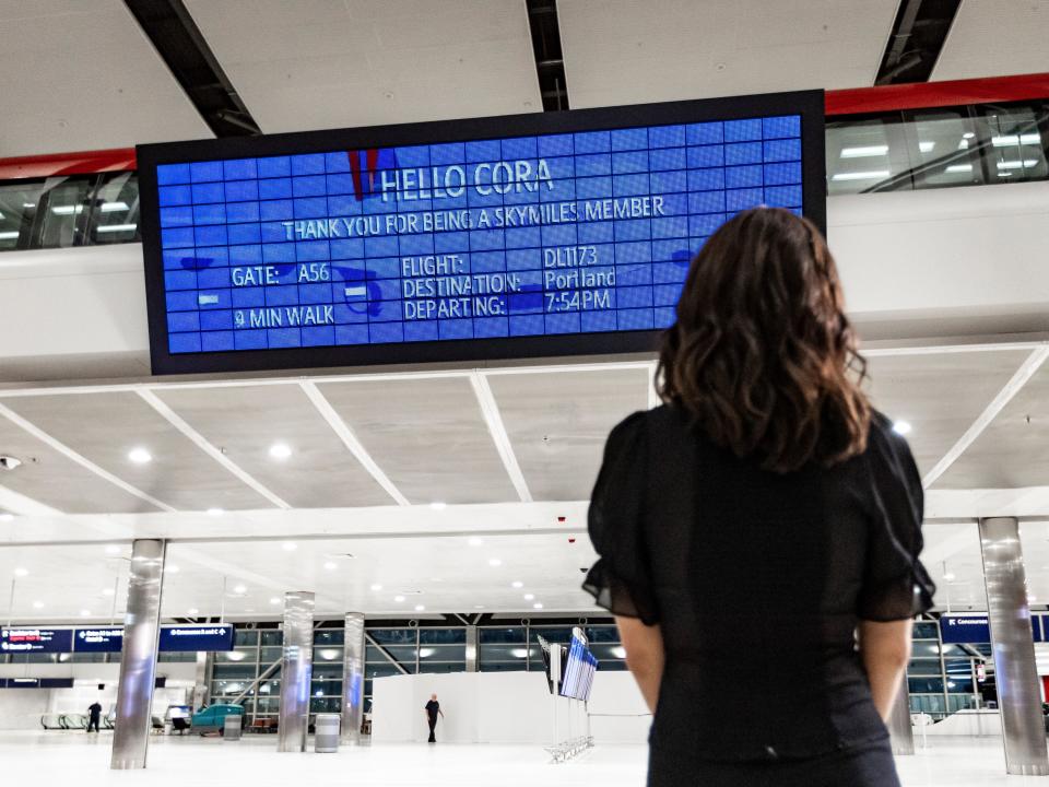 A woman looks at the Parallel Reality board in Detroit's airport, which shows her flight information.