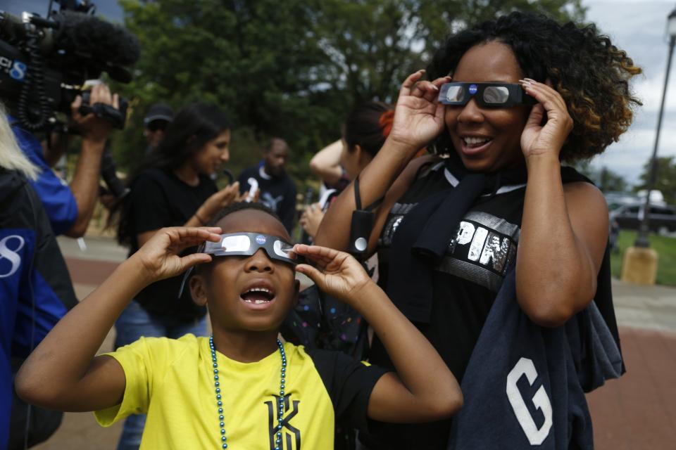 Malon Taylor, 7, takes a look up at the sun alongside mother LaDondra Taylor during a solar eclipse watch party hosted by the Science Center of Iowa outside the Iowa State Capitol in Des Moines.