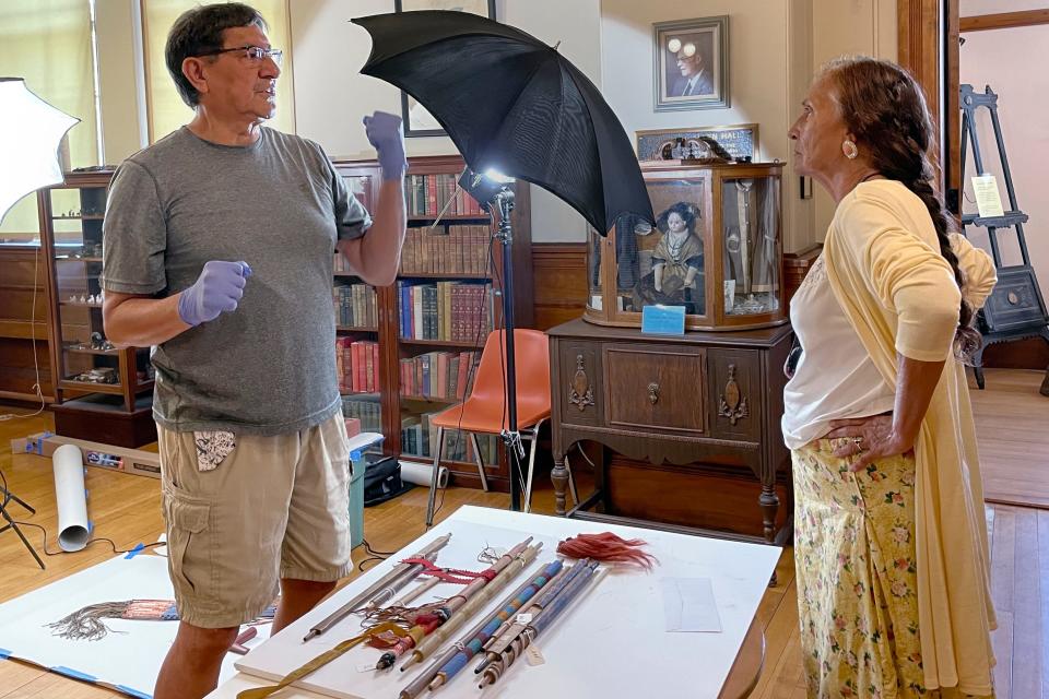 Leola One Feather, right, of the Oglala Sioux Tribe, talks with Jeffrey Not Help Him, left, also an Oglala Sioux tribe member, while Native American artifacts are photographed at the Founders Museum in Barre.