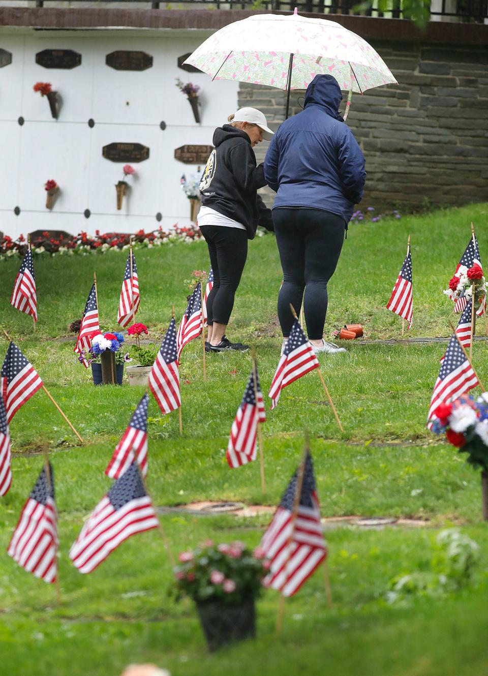 Relatives pay their respects to a veteran at the Garden of Honor in Blue Hill Cemetery in Braintree on Sunday, May 30, 2021.