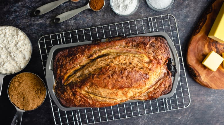 banana bread in loaf pan with containers of raw ingredients