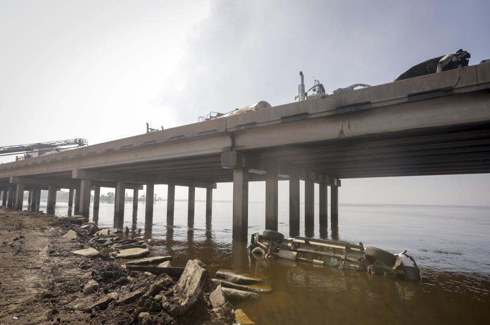 A vehicle is seen in the water below Interstate 55 near Manchac, La., Monday, Oct. 23, 2023. A “superfog” of smoke from south Louisiana marsh fires and dense morning fog caused multiple traffic crashes involving scores of cars Monday, turning I-55 near New Orleans into a narrow junkyard of mangled cars and trucks, some of them burning. (Brett Duke/The Times-Picayune/The New Orleans Advocate via AP)