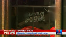 A black flag with white Arabic writing is held up at the window of the Lindt cafe, where hostages are being held, in this still image taken from video from Australia's Seven Network on December 15, 2014. REUTERS/Reuters TV via Seven Network/Courtesy Seven Network