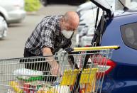 Brian Green, 76, wears a mask as he wheels his supermarket shopping cart to his car outside Pak'nSave supermarket amid the spread of the coronavirus disease (COVID-19) in Christchurch