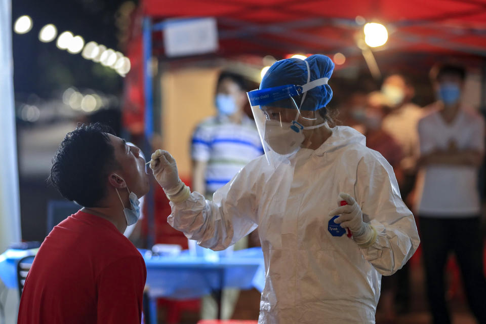 A medical worker takes swab sample from a resident during a round of mass COVID-19 test in Wuhan in central China's Hubei province on Aug. 5, 2021. More than 30 Chinese officials have been fired or received other punishments over accusations they failed to respond properly to the latest surge of the coronavirus in the country. (Chinatopix via AP)