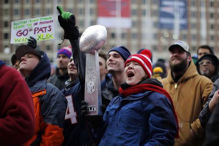 A New England Patriots fan, holding a model of the Vince Lombardi trophy, cheers during a send off rally for the team outside City Hall in Boston, Massachusetts January 26, 2015. REUTERS/Brian Snyder