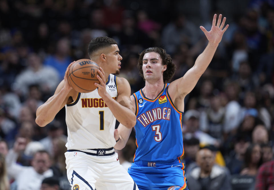 Denver Nuggets forward Michael Porter Jr., left, looks to pass the ball as Oklahoma City Thunder forward Josh Giddey defends in the first half of an NBA preseason basketball game Monday, Oct. 3, 2022, in Denver. (AP Photo/David Zalubowski)