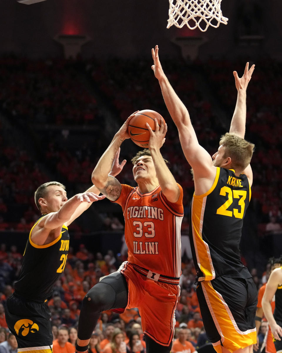 Illinois' Coleman Hawkins (33) scores between Iowa's Payton Sandfort, left, and Ben Krikke during the first half of an NCAA college basketball game Saturday, Feb. 24, 2024, in Champaign, Ill. (AP Photo/Charles Rex Arbogast)