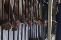 Imprisoned gang members stand behind bars during a media tour of the prison in Quezaltepeque, El Salvador, Friday, Sept. 4, 2020. President Nayib Bukele denied a report Friday that his government has been negotiating with one of the country’s most powerful gangs to lower the murder rate and win their support in mid-term elections in exchange for prison privileges. (AP Photo/Salvador Melendez)