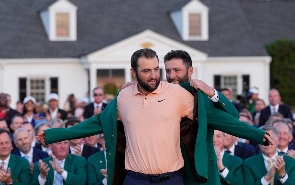 Jon Rahm, of Spain, puts the green jacket on winner Scottie Scheffler