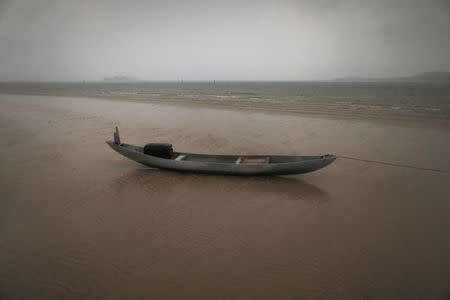 A fishing boat sits on a beach during a rain storm on the east coast of Natuna Besar July 7, 2014. REUTERS/Tim Wimborne
