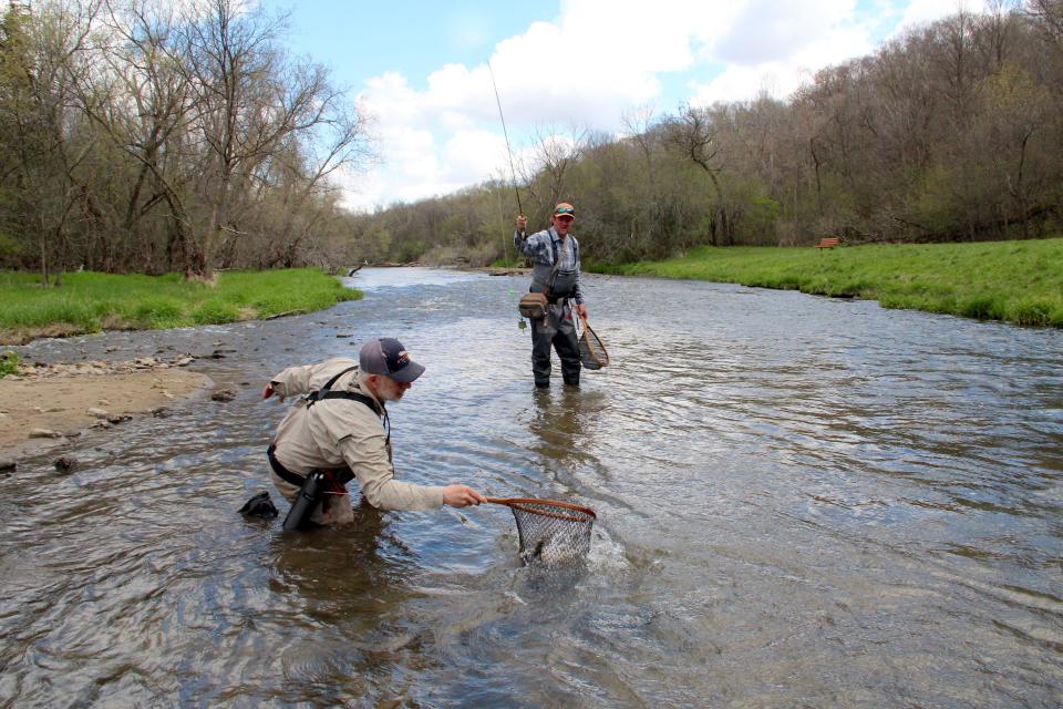 Andy Roth nets a trout for Chris Bye while fishing on the Kinnickinnic River in River Falls. Thanks to local efforts, two dams on the river that produced very little power but substantially warmed the water are being evaluated for removal.