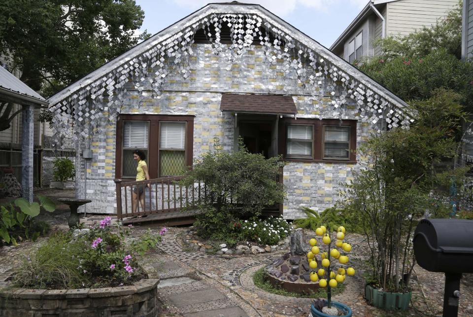 A visitor leaves the back entrance to the beer can house, a Houston landmark, Wednesday, July 10, 2013. Former owner John Milkovisch covered the outside on the house with siding made of cut and flatten beer cans and garlands made from the lids. The Orange Show Center for Visionary Art, a local nonprofit that preserves art installations in the city, bought the property about 10 years ago, restored the house and it opened it to the public. (AP Photo/Pat Sullivan)