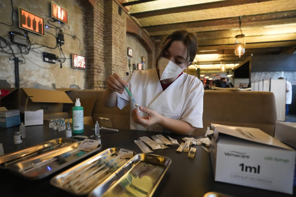 A medical student sits at a dining table as she prepares syringes with vaccination against the coronavirus and the COVID-19 disease inside the Sage Beach Bar and Restaurant in Berlin, Germany, Monday, Jan. 3, 2022. The Clubcommission Berlin, an association that protects and supports the Berlin club culture, start a vaccination campaign which take place in several clubs bars and restaurants in the German capital. (AP Photo/Markus Schreiber)